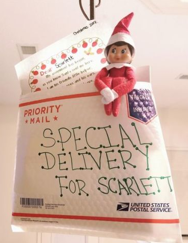 Christmas elf arrival idea showing an elf doll jumping out of a USPS mailing envelope labeled "SPECIAL DELIVERY FOR SCARLETT"