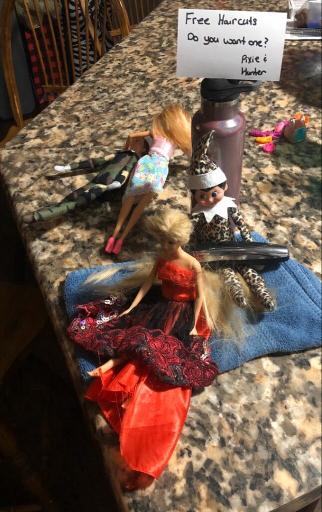 Elf on the shelf dolls giving barbie dolls a hair cut.