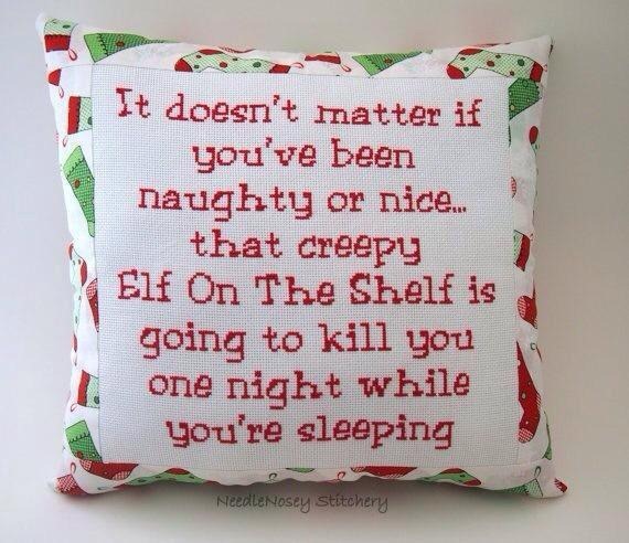 A pillow with Christmas stocking fabric and cross stitched text that reads: It doesn't matter if you've been naughty or nice... that creepy Elf on the Shelf is going to kill you one night while you're sleeping.