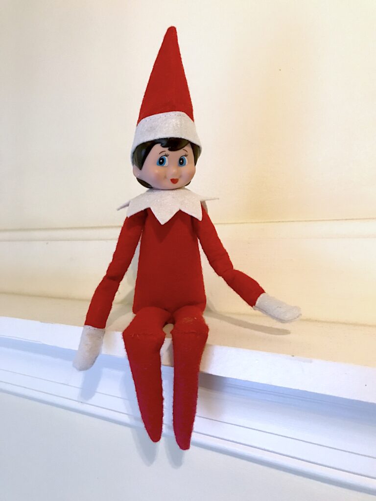 an elf on the shelf girl doll sitting on a mantel
