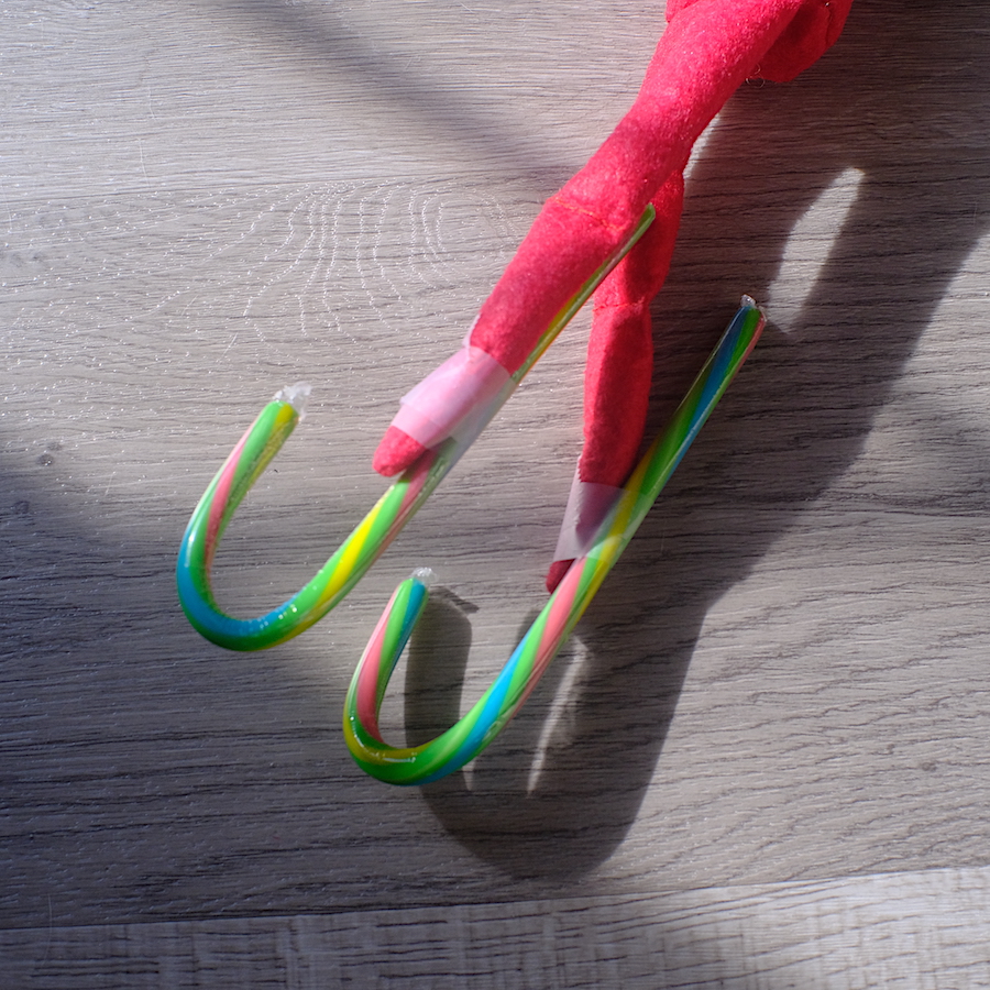 A photo illustrating how the candy canes are taped to the elves legs.